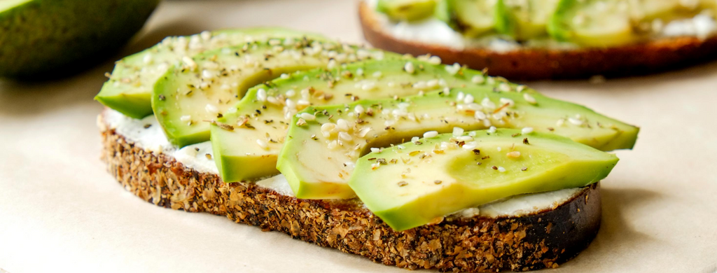 A slice of sourdough bread topped with avocado and seasonings